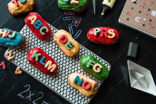 Colorful eclairs with letters next to notebook and planner  back to school concept