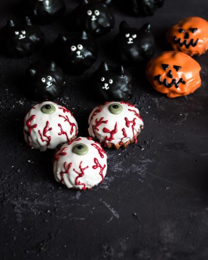 A vertical shot of eclairs with Halloween decorations on black background