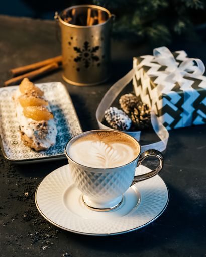 A vertical shot of a cup of coffee and an eclair in a restaurant