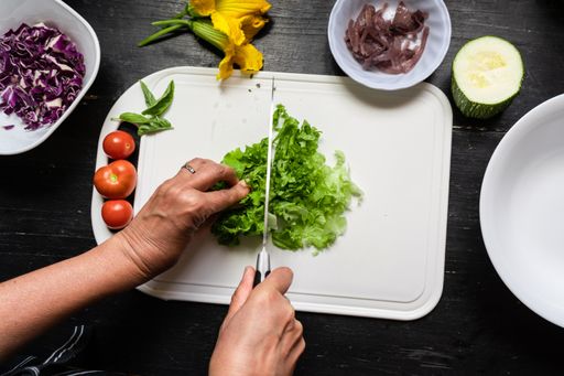 A top view of Chef's hands chopping lettuce on a white board