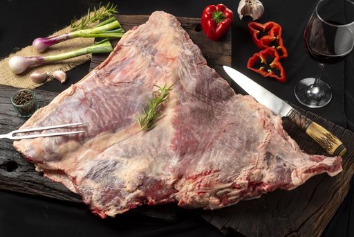 A closeup of a raw meat tenderloin on wooden cutting boards surrounded with vegetables and spices