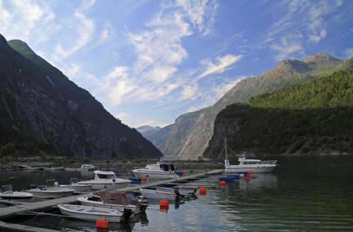 A beautiful shot of a lake with boats near the dock under a blue sky surrounded by mountains