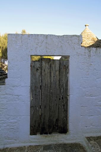 A vertical shot of a wooden door on a white wall