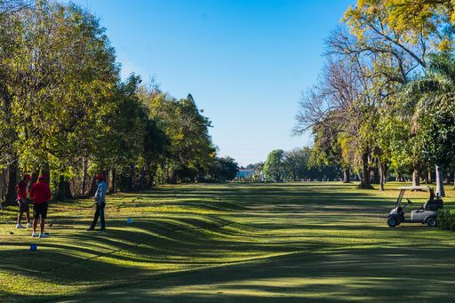 view of an incredible golf course with the silhouette of unrecognizable people while playing golf at noon