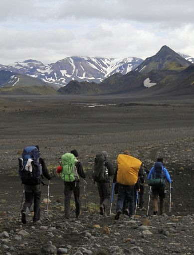 A vertical shot of people hiking towards the mountain in the distance