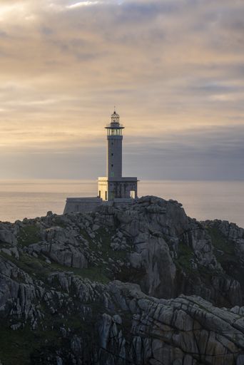 The lighthouse of Punta Nariga in the background of the dramatic sunset sky (Galicia, Spain)