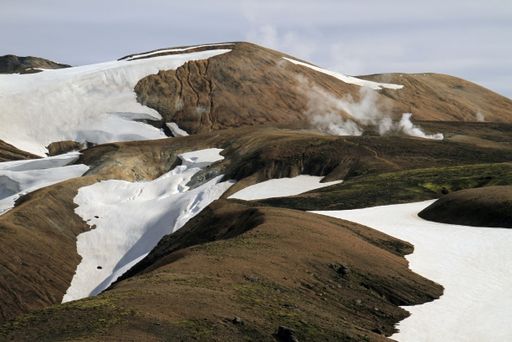 A beautiful shot of mountains with patches of snow under a cloudy sky - great for background