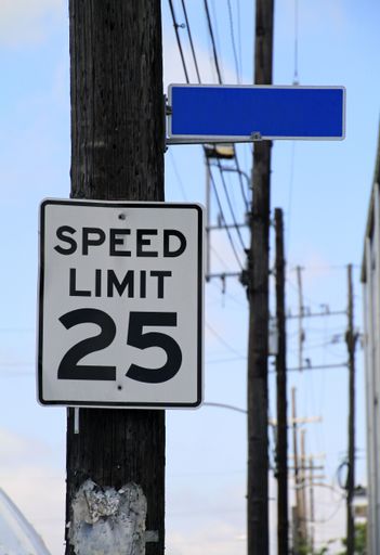 A vertical shot of a speed limit sign on a wooden tree
