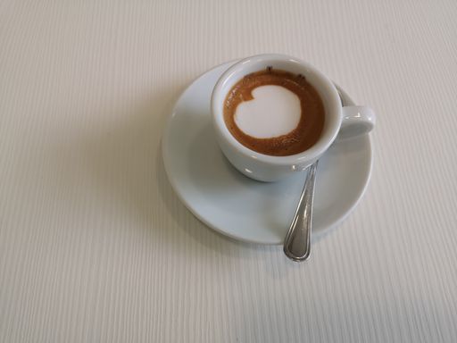 A closeup shot of a coffee latte in a white cup and saucer