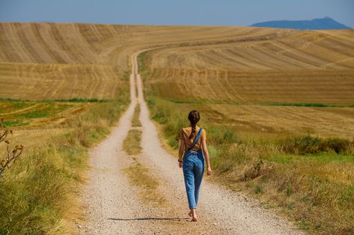 A closeup shot of a young female walking on a path in the field