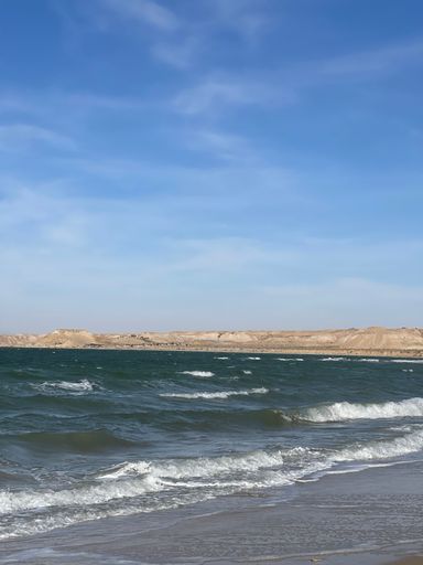 A vertical of sandy Dakhla beach against the sea waves on a sunny day