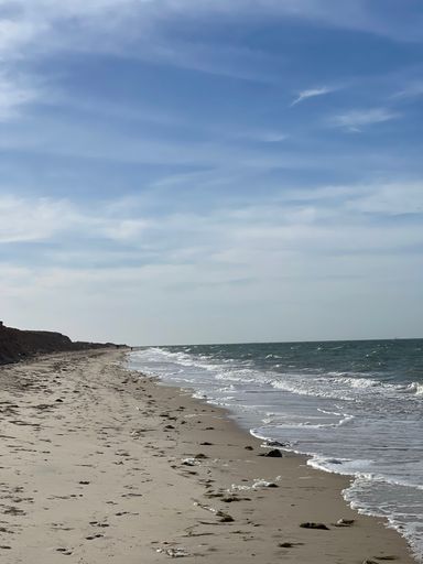 A vertical of sandy Dakhla beach against the sea waves on a sunny day