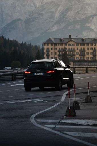 A vertical shot of a car driving in the Dolomites mountains in Italy