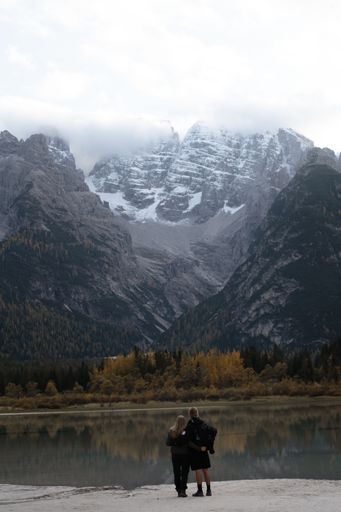 A young couple hugging and standing near the Durrensee lake surrounded by rocky hills in Italy