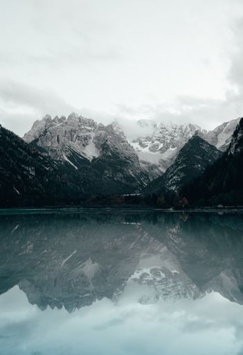 A vertical shot of the Durrensee lake surrounded by rocky hills under a cloudy sky in Italy