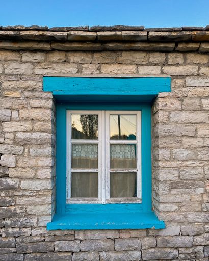 A vertical shot of an old blue painted window on a stone wall