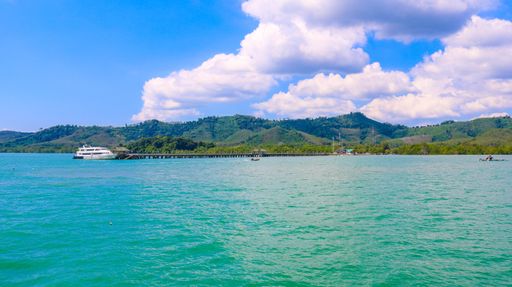 A beautiful landscape surrounded by mountains on the ocean gleaming under the cloudy blue sky