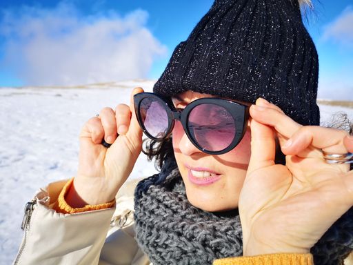 A closeup shot of a young female wearing sunglasses in the snowy mountains