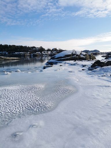 A vertical shot of the cliffs by a frozen lake in Sukkersletta, Larvik during a sunny winter day