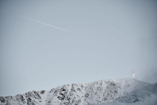 A plane flying over a snow covered mountain range near ski slope