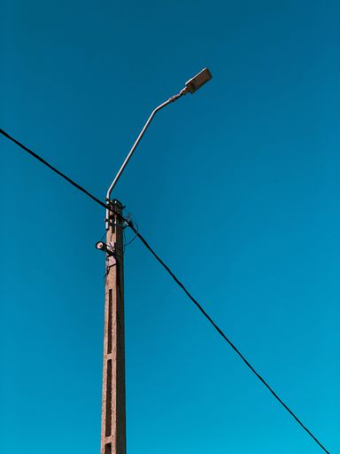 A low angle shot of a street light on a pole under a clear blue sky
