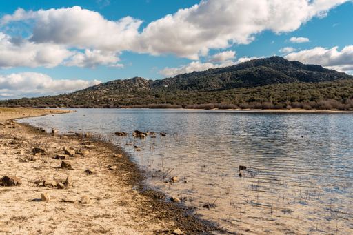 sandy beach with rocks and water and a mountain in the background