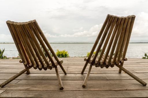 A closeup shot of two chairs in front of the ocean under a cloudy sky