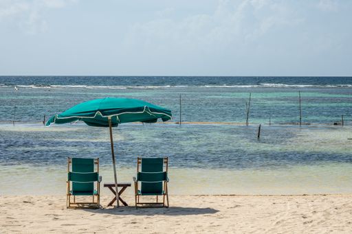 Two chairs and a large umbrella on the beach on a clear sunny day