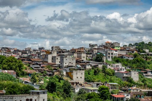 A wide angle shot of a city full of trees and buildings under a cloudy sky during daytime