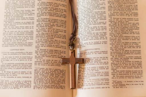 A wooden cross necklace on a page of the bible