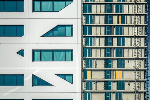 A closeup shot of a modern building made of white walls and glass windows