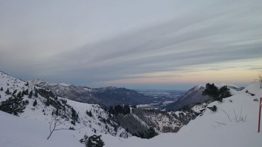 A scenic view of a mountain range covered with snow at sunset