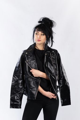 A fashion model from Bosnia and Herzegovina in a leather jacket posing against a white background