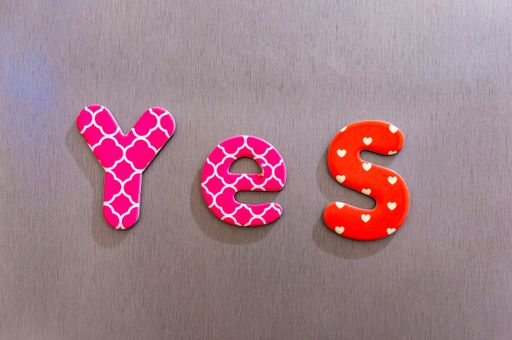 The word yes made of colorful magnetic letters on a brown background