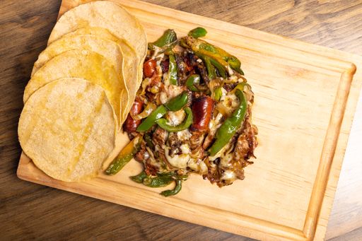 A top view of Traditional Mexican food (Chistorra tacos with cheese) on a wooden board