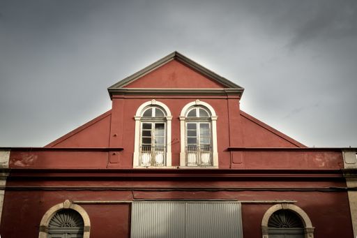 A low angle shot of a red building under dark storm clouds