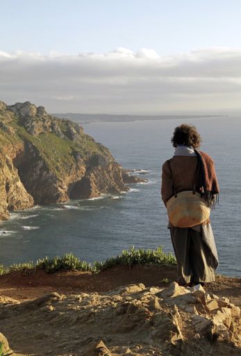 A vertical shot of a woman standing near the Cabo da Roca in the city of Colares, Portugal