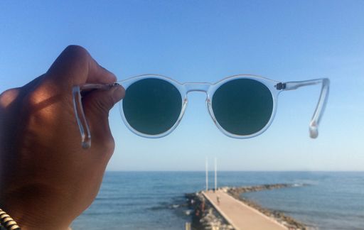 A wide angle shot of an ocean seen through sunglasses under a clear blue sky