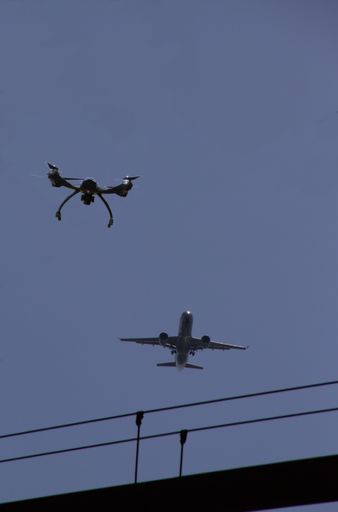 A vertical shot of a drone and an airplane flying in the air