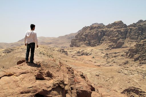 A wide angle shot of a man standing on a cliff in a desert