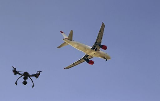 A low angle shot of an airplane and a drone flying next to each other