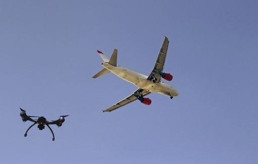 A low angle shot of an airplane and a drone flying next to each other