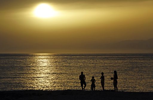 The silhouettes of people standing on the beach during a sunset