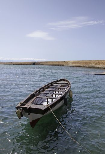A vertical shot of a boat on the water under a clear blue sky