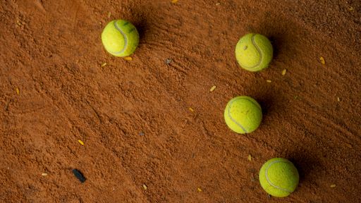 A top view of four tennis balls scattered on the court ground