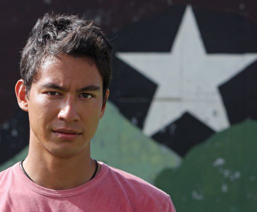 A closeup shot of a man dressed in pink behind a star on the wall