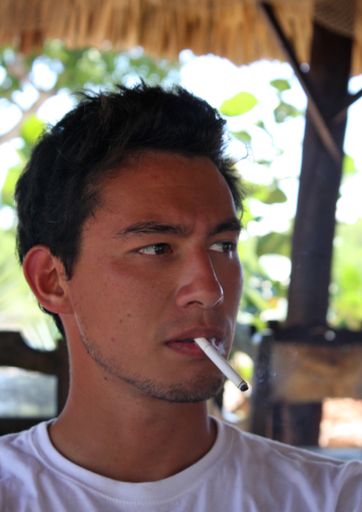 A vertical shot of a man smoking a cigarette during daytime