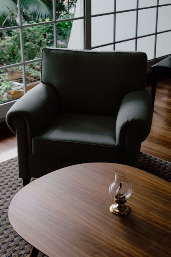 A wooden table with an armchair against the background of large windows overlooking the garden