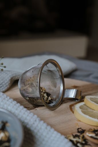 A selective focus shot of small metal strainer with dry tea