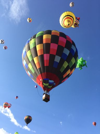 A vertical shot of colorful hot air balloons flying in the blue sky